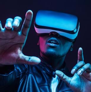 Man wearing virtual reality goggles with hands up, isolated on black background