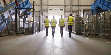 Four colleagues in reflective vests leaving a warehouse