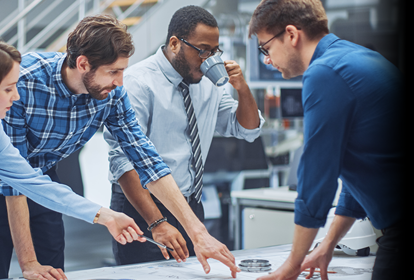 Group of engineers discussing plans around a desk