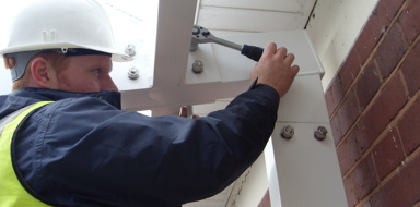 Twinfix staff member in a hard hat tightening bolts on a building