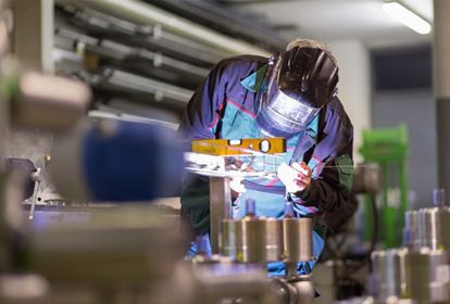 Factory worker using a welding torch to fabricate metal