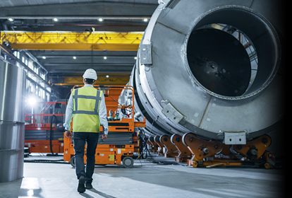 Engineer in a hard had walking across an engineering factory shop floor