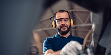 Factory worker operating band saw cutting machine for steel bars in the industrial factory