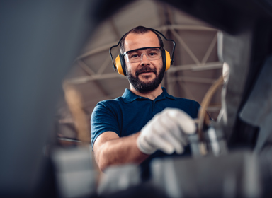 Factory worker operating band saw cutting machine for steel bars in the industrial factory