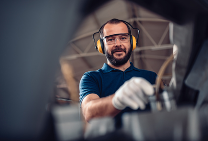 Factory worker operating band saw cutting machine for steel bars in the industrial factory