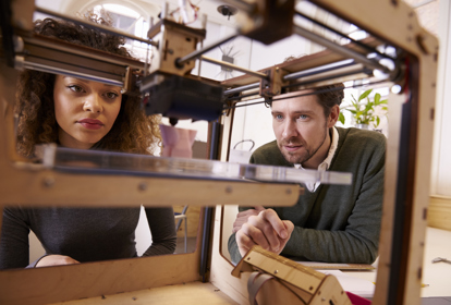 Two Designers Working With 3D Printer In Design Studio