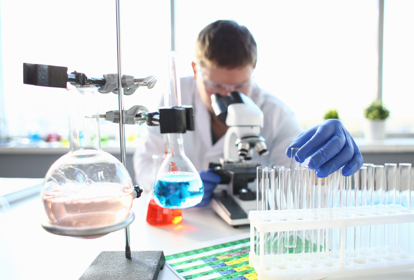 Portrait of a young chemist looking in binocular