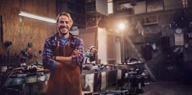 Portrait of smiling mechanic standing in garage workshop with professional equipment
