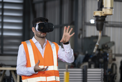 Male factory worker operating a robotic arm using a virtual reality headset