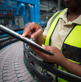 Mid section of factory worker using digital tablet in the factory