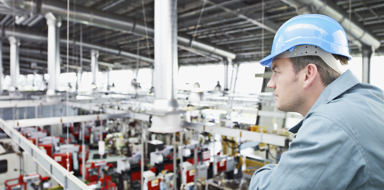 Factory-worker in hard-hat looking at factory floor