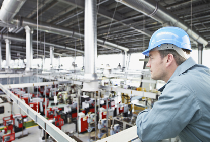 Factory-worker in hard-hat looking at factory floor