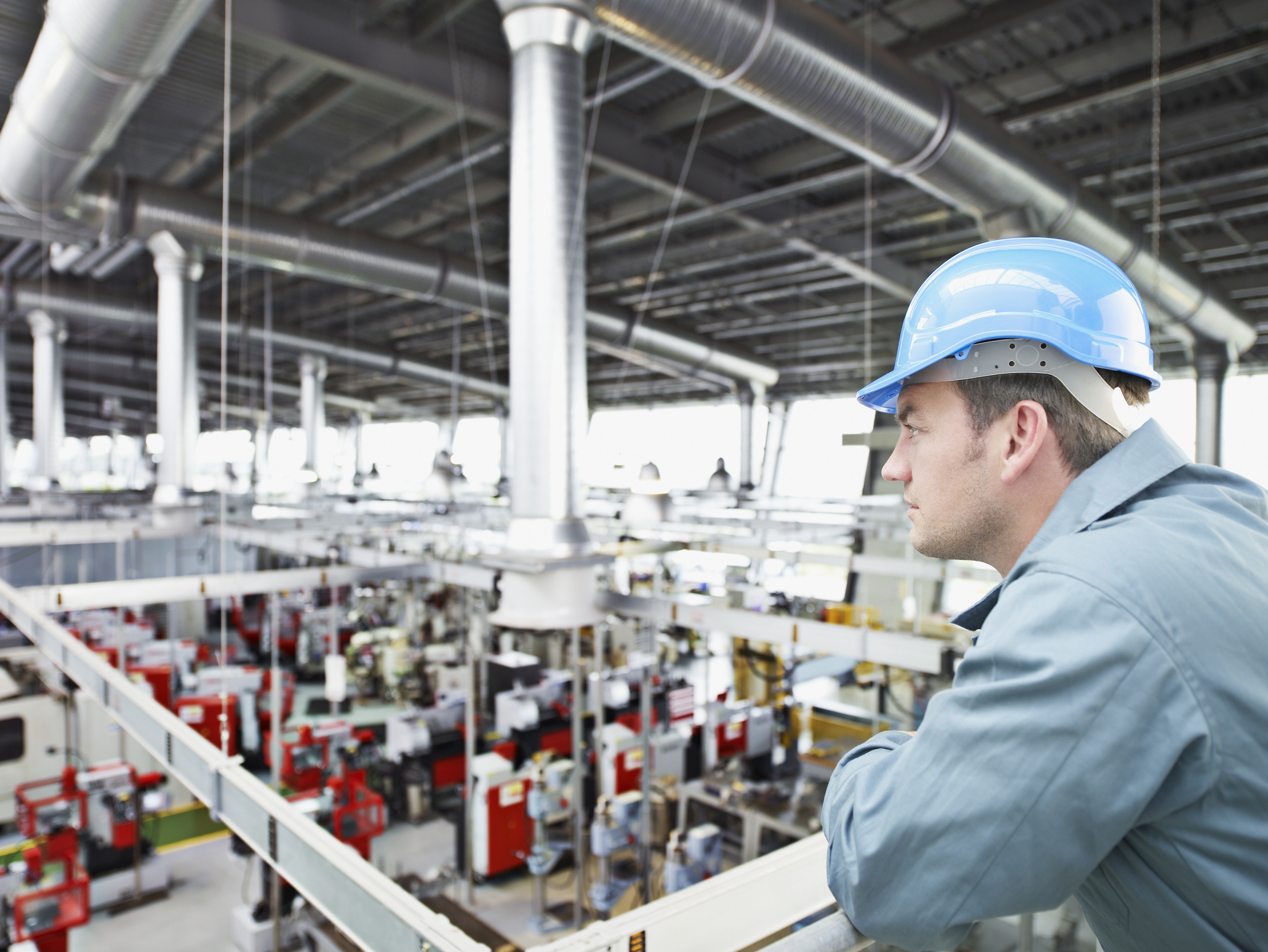 Factory-worker in hard-hat looking at factory floor